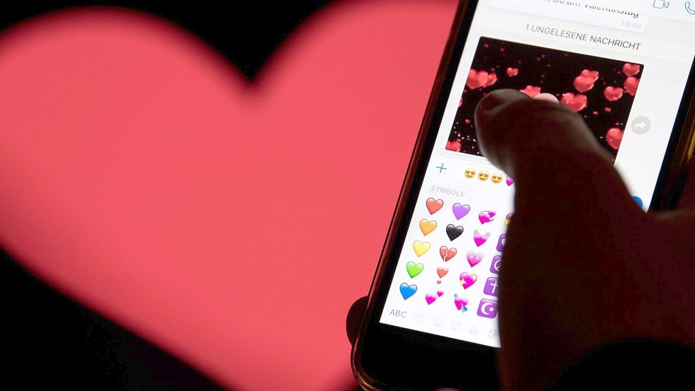 Hand aufs Handy - das rote Herz zählt zu den beliebtesten Emojis. (Archivbild) Foto: Fabian Sommer/dpa