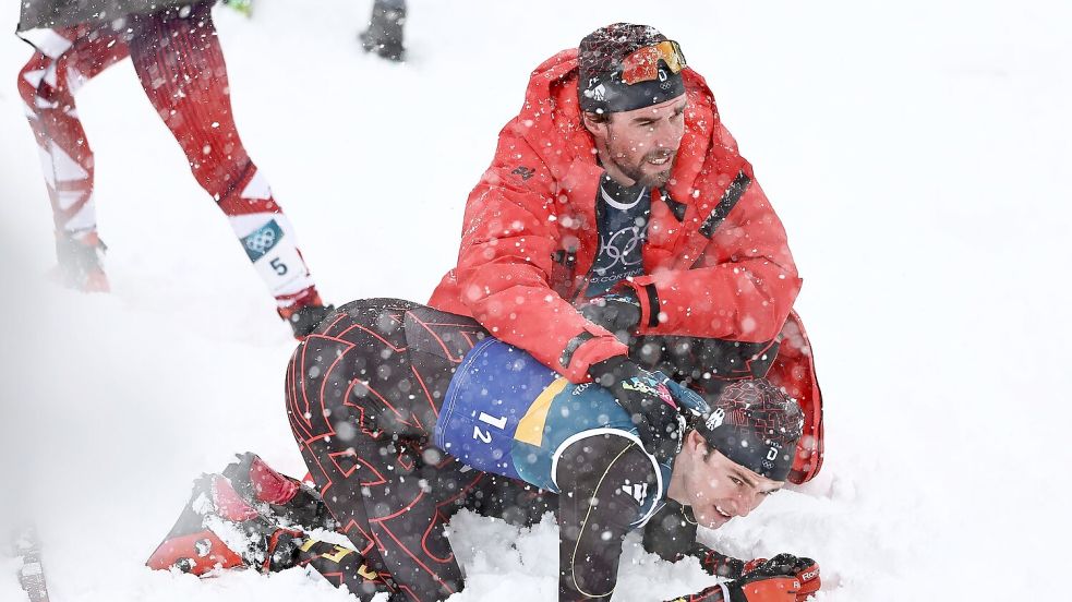 Vinzenz Geiger liegt im Schnee und wird von Teamkollege Johannes Rydzek getröstet. Foto: Daniel Karmann
