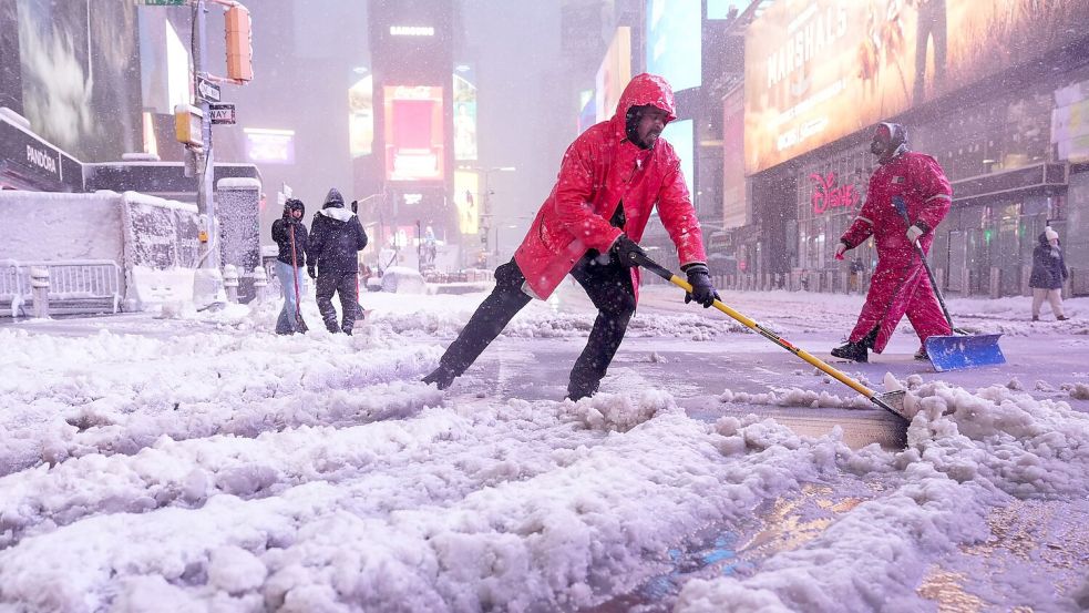 Ein Arbeiter schaufelt Schnee auf dem Times Square in New York. Ein heftiger Schneesturm zieht über den Nordosten der USA hinweg. Foto: Seth Wenig/AP/dpa