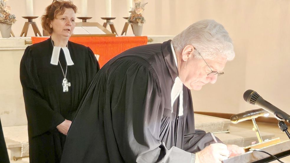 Superintendent Thomas Kersten unterzeichnet die Fusions-Urkunde. Im Hintergrund schaut Regionalbischöfin Sabine Schiermeyer zu. Foto: Klaus Averberg