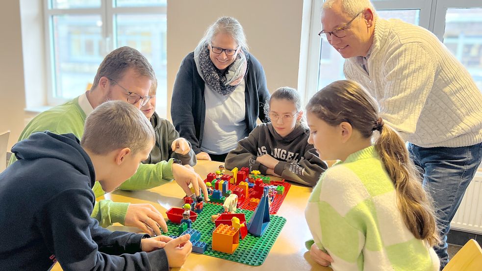Das neue Konzept für selbstständiges Lernen wurde für einen Videoclip mit Legosteinen nachgebaut. Hier wird es von Schulleiter Christian Hunsmann (rechts), Lehrkraft Anne Paschmann (Mitte) und Fokko Peters, Stufenleiter Klasse 7 bis 9, einigen Schülerinnen und Schülern demonstriert. Foto: Annette Kisch/FCSO