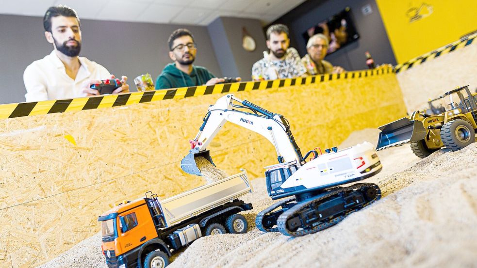 Gründer Siymo Othman (links) steuert mit Freunden kleine Bagger, Radlader und Lastwagen in seinem neu eröffneten Bagger-Café. Es soll das erste dieser Art in Deutschland sein. Foto: Moritz Frankenberg