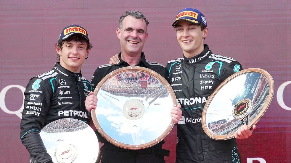 George Russell (r) freut sich über Silbergeschirr. Foto: Scott Barbour/AP/dpa