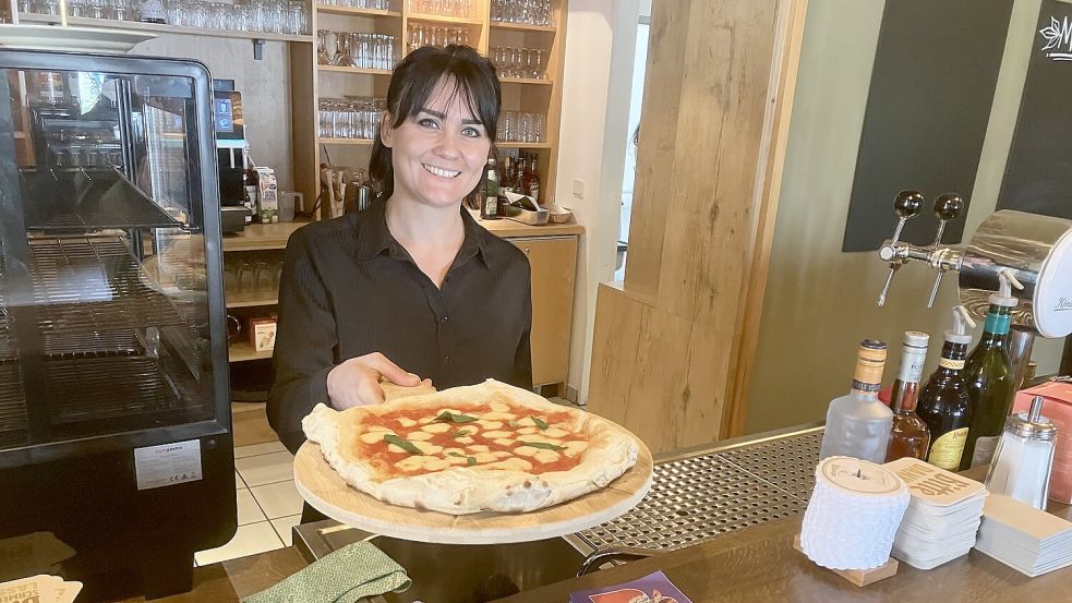 Frisch aus dem Ofen reicht Angelique Schönewald eine handgemachte Pizza über den Tresen der umgebauten Theke im Bistro „Kiek in“ am Campingplatz Papenburg. Foto: Gerd Schade