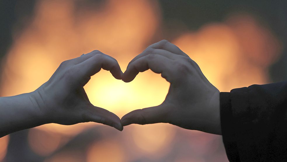 Besucher formen vor einem Osterfeuer ein Herz. Es werden in vielen Orten Osterfeuer entzündet. Foto: Matthias Bein/dpa