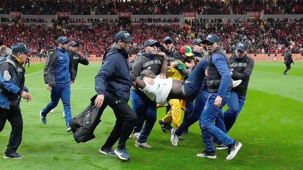 Ein auf den Platz gestürmter Anhänger des Senegals wurde von Sicherheitskräften weggetragen. (Archivbild) Foto: Themba Hadebe/AP/dpa