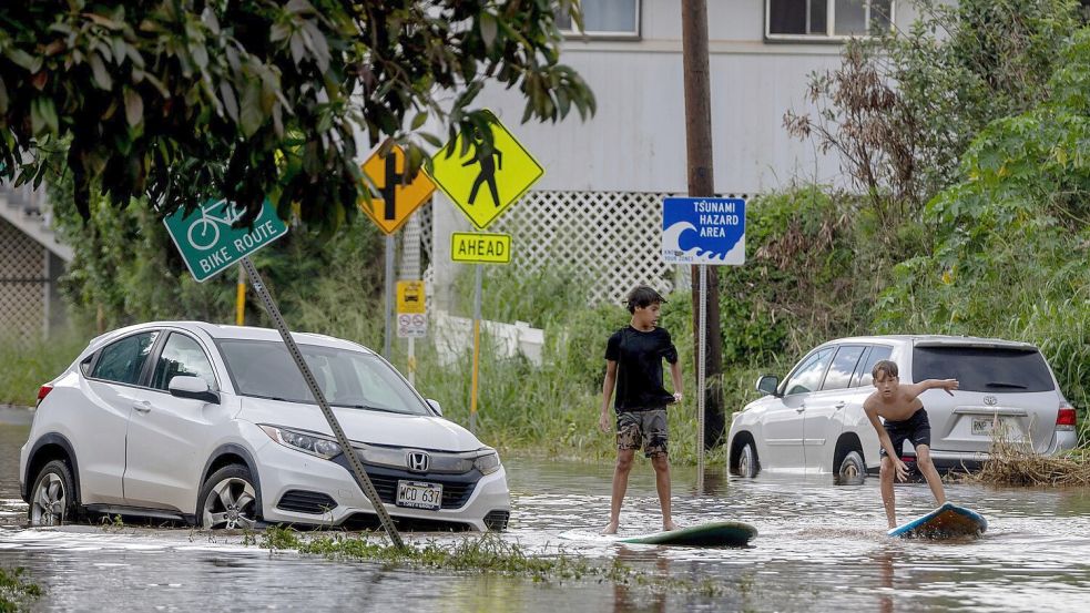 Zwei Jugendliche surfen in Waialua neben einem liegengebliebenen Fahrzeug im Hochwasser. Foto: Stephen Lam/San Francisco Chroni