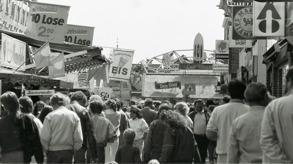 Dichtes Gedränge am Sonntagnachmittag: Der Blick fällt von der Norderstraße auf dem Marktplatz. Volksfest und geöffnete Geschäfte waren ein Garant für eine von Menschen gefüllte Innenstadt. Im Bildhintergrund ist der Karussellklassiker „Hollywood Lift“ zu erkennen. Davor prangt der Schriftzug der Wurstbude von Leo Werth, die heute von Angelo Kanzler betrieben wird. Foto: Heinz-Werner Theesfeld