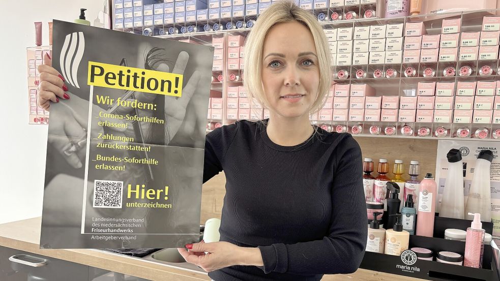 Janna Follrichs (34), Inhaberin des Salons „The Look“ in Rhauderfehn, hält ein Plakat zur Petition gegen die Rückforderungen der Corona-Soforthilfe hoch. Foto: Henrik Zein