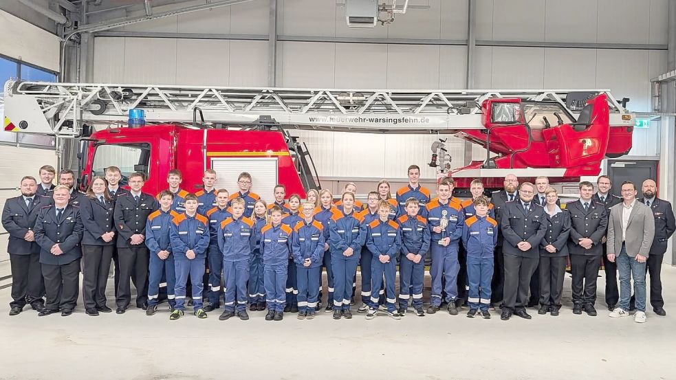 Die Mitglieder der Jugendfeuerwehr Warsingsfehn und ihre Gäste stellten sich bei der Jahreshauptversammlung vor der neuen Drehleiter zum Foto auf. Foto: Bodo Wolters