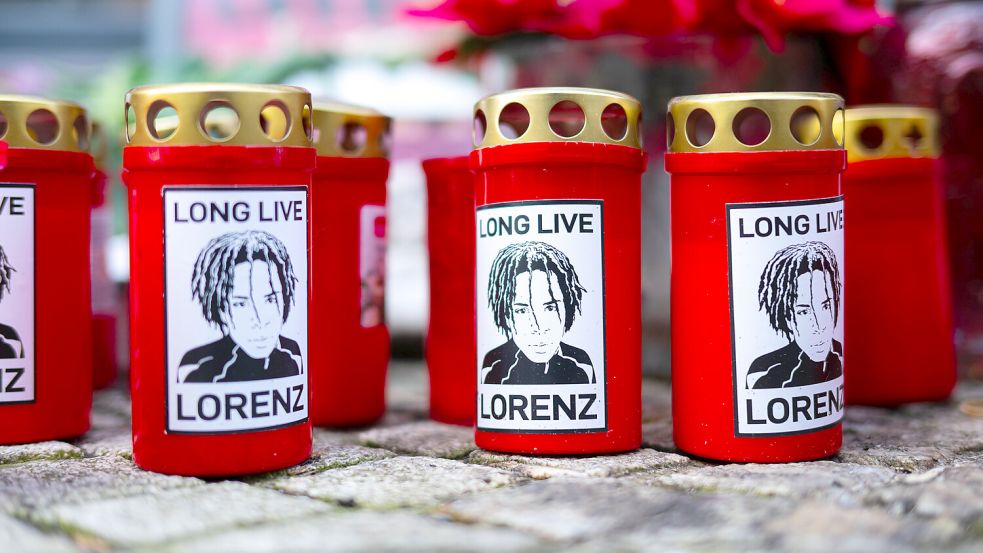 „Long live Lorenz“ steht auf roten Grablichtern. Ein Jahr nach Lorenz‘ Tod legen noch immer Menschen Blumen, Kerzen und Plakate am Tatort nieder. Ein Polizist schoss in der Nacht zu Ostersonntag 2025 mehrfach auf den jungen Mann in der Oldenburger Fußgängerzone. Der 21-Jährige starb kurze Zeit später im Krankenhaus. DPA-Foto: Sina Schuldt