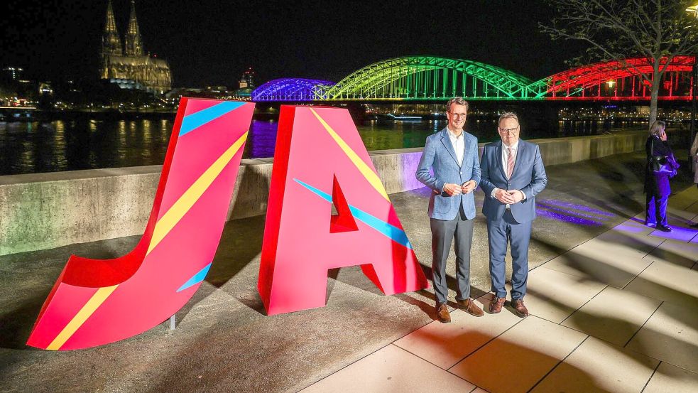 Ministerpräsident Hendrik Wüst (l) und Kölns Oberbürgermeister Torsten Burmester freuen sich über das Ja beim Olympia-Entscheid. Foto: Christoph Reichwein