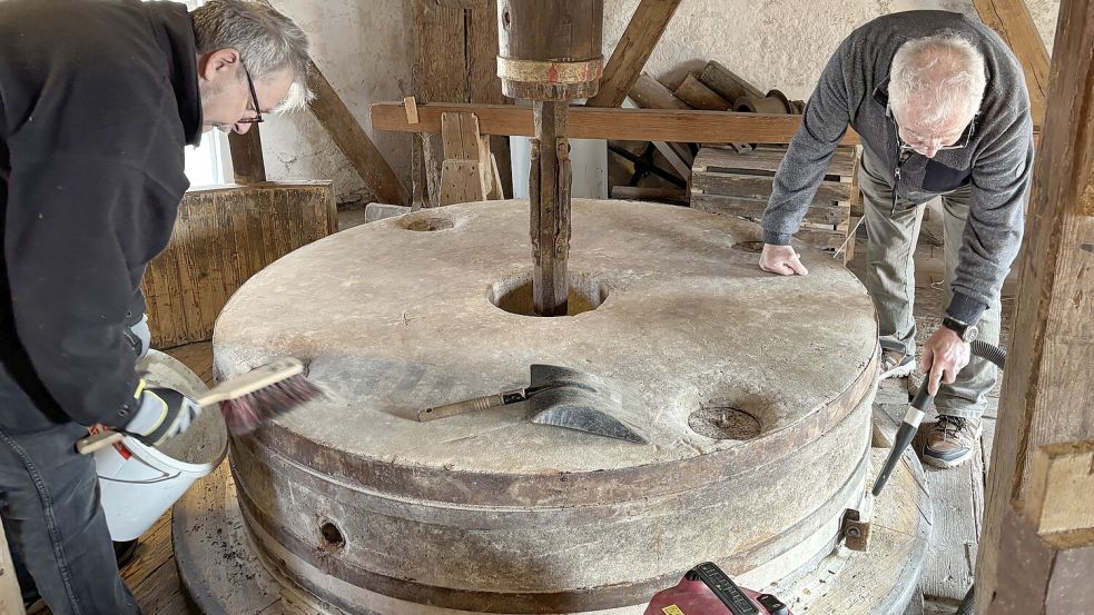 Mit Handfeger und Staubsauger wird der Mahlstein auf Hochglanz gebracht. Uwe Hänsch und Günther Meidenbauer sagen Mehlresten, Staub und einer Menge Mäuseköttel den Kampf an. Foto: Susanne Ullrich