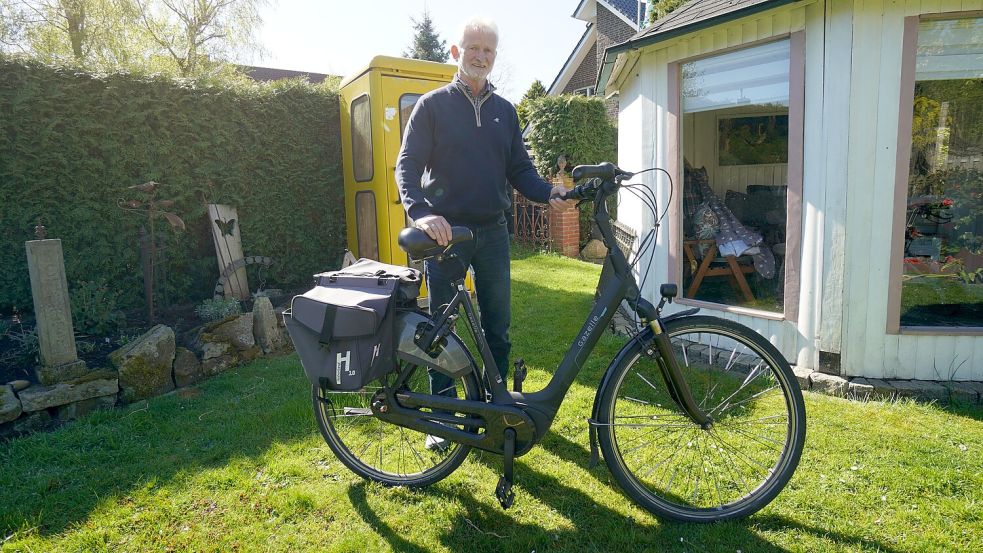 Hat sich mittlerweile auch ein E-Bike zugelegt: Hans Schütte in seinem Garten – mit ehemaliger Telefonzelle. Foto: Mirco Moormann
