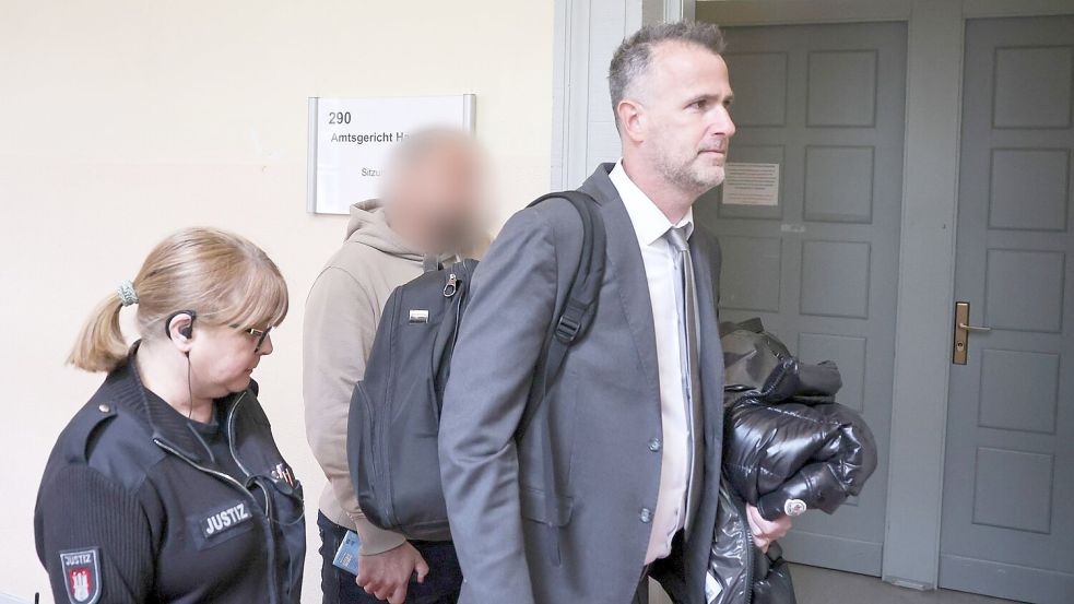 Der Zeuge (Mitte des Bildes) wird von seinem Anwalt (rechts im Bild) in den Gerichtssaal begleitet. Foto: Christian Charisius