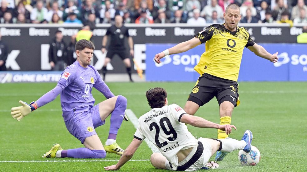 BVB-Torwart Gregor Kobel (l) und Waldemat Anton (r) im Duell mit Gladbachs Joe Scally. Foto: Federico Gambarini