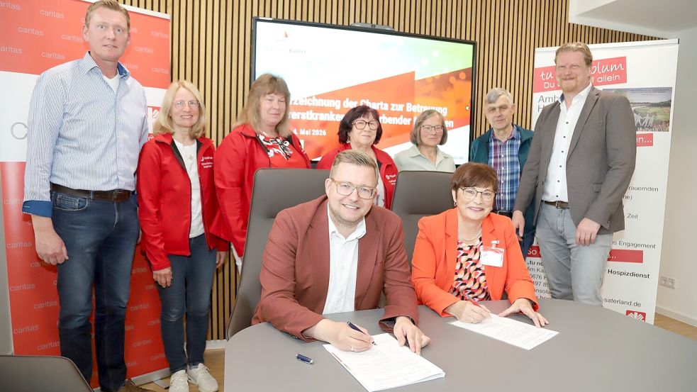 Bürgermeister Nils Anhuth (sitzend, links) unterzeichnet die Charta zusammen mit der Koordinatorin Marlies Steenken (rechts). Über die Schulter schauen den Beiden Erster Gemeinderat Michael Sope (stehend links), Carsten Huslage (rechts) sowie haupt- und ehrenamtliche Kräfte. Foto: Hans Passmann