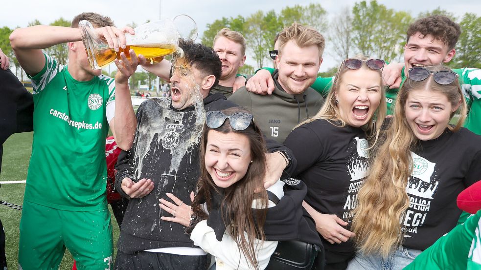 Bei den Aufstiegsfeierlichkeiten gab es natürlich auch die obligatorische Bierdusche für Trainer Jannik Swieter. Der wurde im wahrsten Sinne des Wortes „kalt erwischt“. Das Team hatte sich gerade zum Gruppenbild mit den Partnerinnen aufgestellt, als Tim Röpkes sich von hinten heranschlich. Swieters Freundin Elena (vorne) ging rechtzeitig in Deckung. Fotos: Jens Doden/ Emden