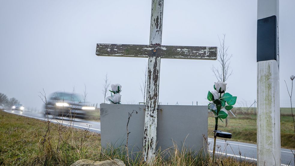 Ein Auto fährt auf einer Landstraße an einem hölzernen Kreuz vorbei, welches zur Erinnerung an ein Unfallopfer aufgestellt wurde. Foto: dpa/Jens Büttner