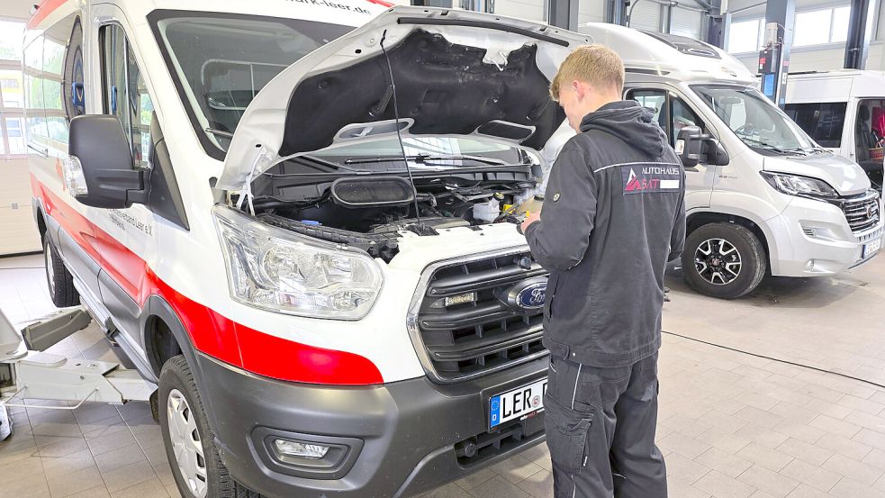 Die moderne Werkstatt bietet auch Platz für größere Fahrzeuge. Hier ist Kfz-Meister Jannik Schaaf mit der Wartung eines Rettungswagens beschäftigt. Im Hintergrund ist ein Wohnmobil zu sehen.
