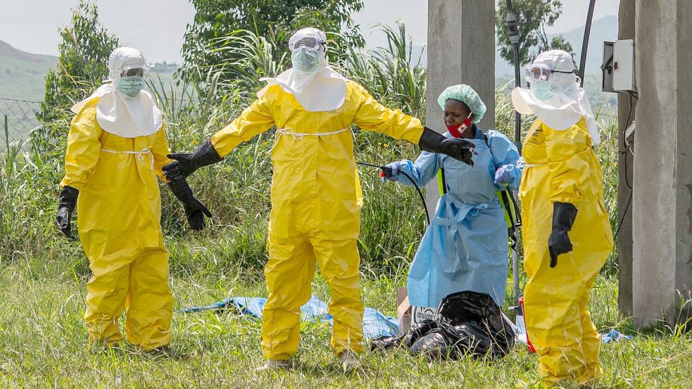 Mitarbeiter des Roten Kreuzes in Schutzkleidung desinfizieren sich. Foto: Moses Sawasawa