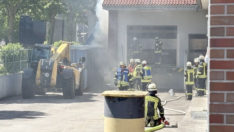 Die Feuerwehr bekam Unterstützung von einer nahegelegenen Baustelle. Ein Mitarbeiter zog mit schwerem Gerät den Container vor. Anschließend konnten die Einsatzkräfte das brennende Papier besser löschen. Foto: Carsten Ammermann