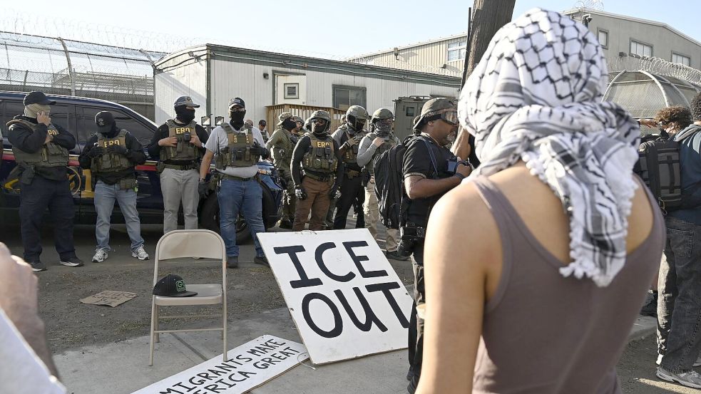 Vor Bundesbeamten der Einwanderungsbehörde ICE haben Demonstrierende ein großes Schild mit der Aufschrift „ICE out“ drapiert. Foto: Anne Pollmann/dpa