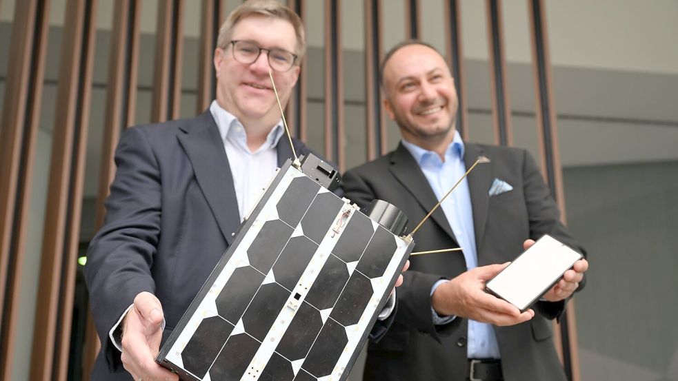 Demonstrativ gute Laune von O2-Manager Jörg Kablitz und OQ-Chef Omar Qaise, die bei der Vorstellung ihres Vorhabens ein Modell eines Satelliten dabeihatten. Foto: Wolf von Dewitz/dpa