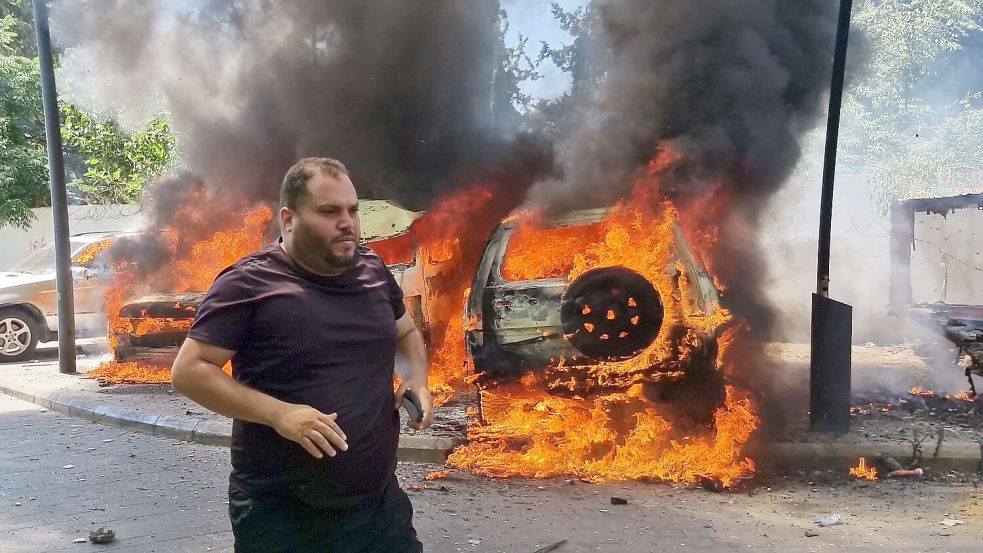 Ein Mann läuft vor brennenden Autos, die bei einem israelischen Luftangriff in der libanesischen Hafenstadt Sidon in Brand geraten sind. Foto: Mohammed Zaatari