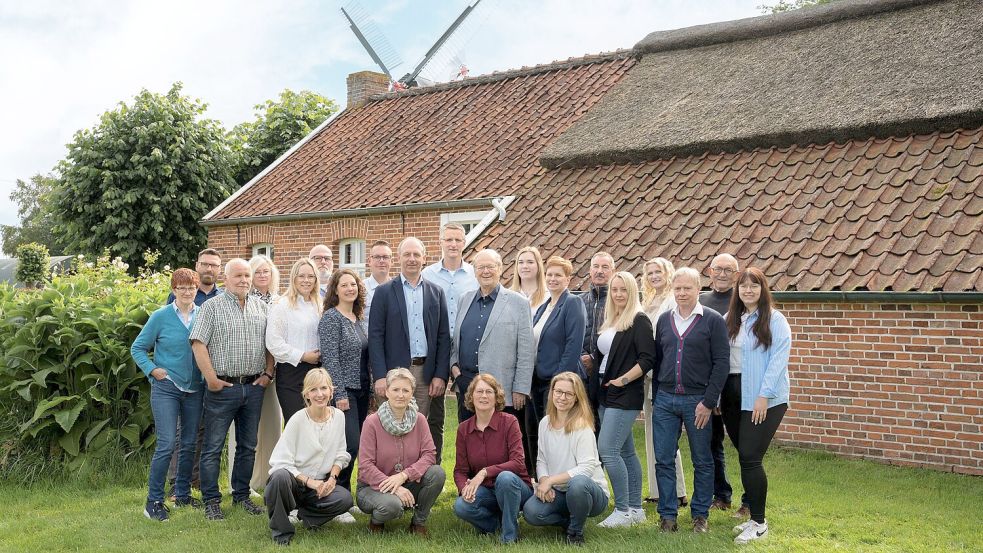 Geballte Erfahrung und Verlässlichkeit: Firmengründer Dieter Baumann (mittlere Reihe, Sechster von links) mit seinem Team im Garten von „Heiten‘s Huus, einem historischen Gebäude in Warsingsfehn. Foto: Bebold Werbeagentur