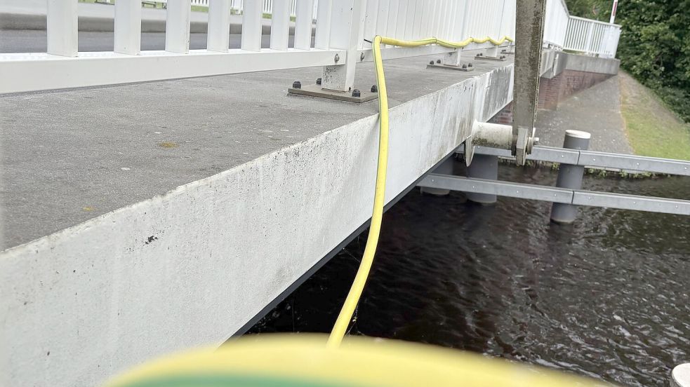 Eine Tauchpumpe fördert das Wasser durch einen Schlauch auf die Mitte der Brücke am Grünen Weg in Aurich. Von dort läuft es bei Hitze über die Bauteile und kühlt sie. So wird eine Ausdehnung des Materials verhindert. Foto: Lasse Paulsen