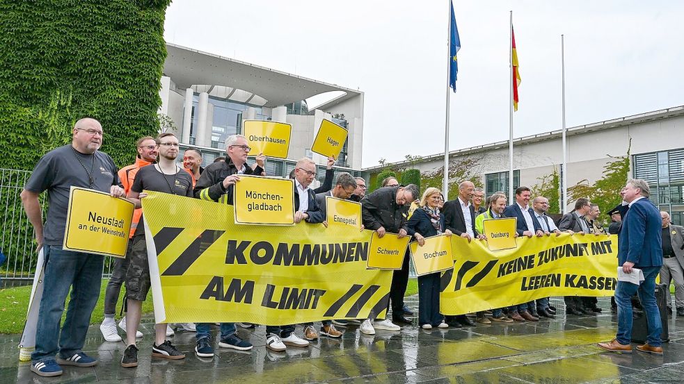 Vertreter mehrerer Städte und Kommunen demonstrieren mit Schildern und Bannern für finanzielle Unterstützung in Berlin. Foto: Jens Kalaene