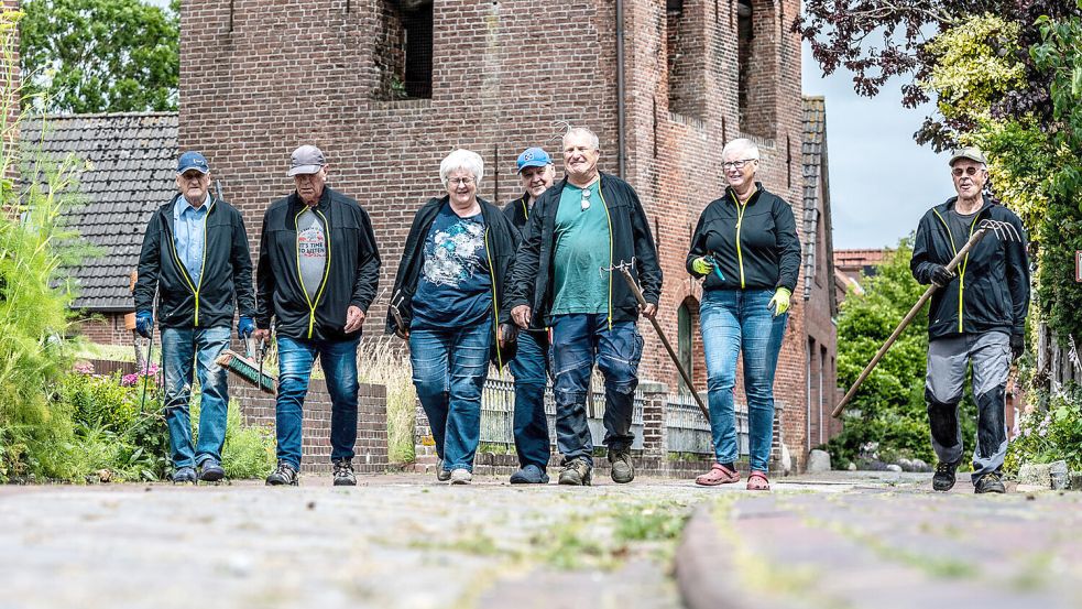 Die Pilsumer Laugputzer in Aktion: Mit Harke, Laubbläser und Heckenschere bringen sie rund um die Kreuzkirche und das Gefallenen-Denkmal Beete und Wege auf Vordermann. Fotos: Klaus Ortgies