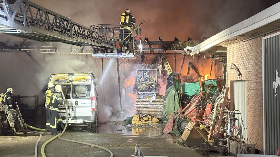 Der große Schuppen im Hintergrund wurde durch das Feuer zerstört. Die Flammen griffen zudem auf einen Transporter über. Im Einsatz war auch die Drehleiter der Feuerwehr Westrhauderfehn. Foto: Carsten Ammermann
