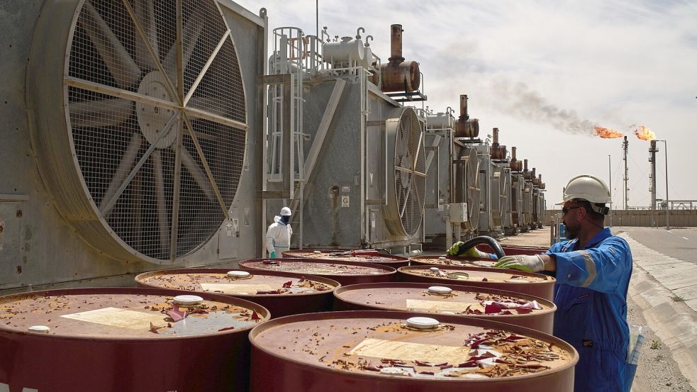 Ein Arbeiter steht an Öltonnen, während er an einer Entgasungsstation im Zubair-Ölfeld in der Nähe von Basra arbeitet. Der Betrieb auf dem Ölfeld ist aufgrund des Iran-Kieges eingeschränkt. (zu dpa: „Irak prüft Bau einer neuen Ölpipeline zum Mittelmeer“) Foto: Leo Correa/AP/dpa