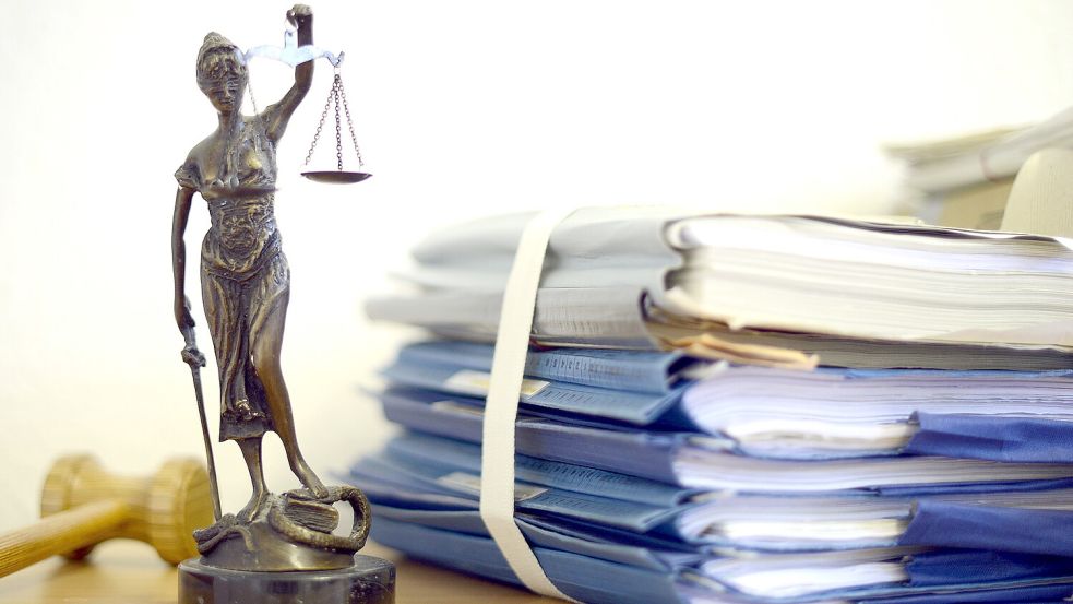Eine Figur von Justitia steht neben einem Stapel Akten. Foto: DPA