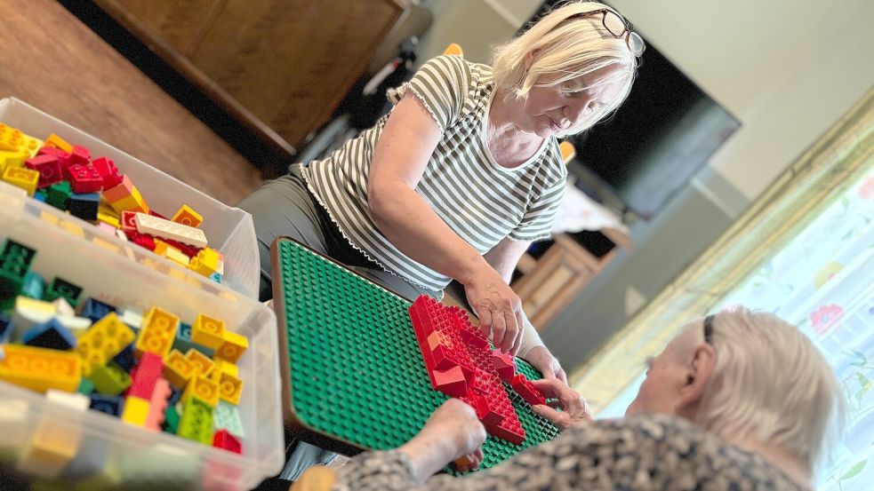 Monika Duis sitzt vor ihrer Mutter. Ihre Mutter leidet an Demenz. Zwischen den beiden ist eine Bauplatte für Klemmbausteine. Foto: Lars Löschen