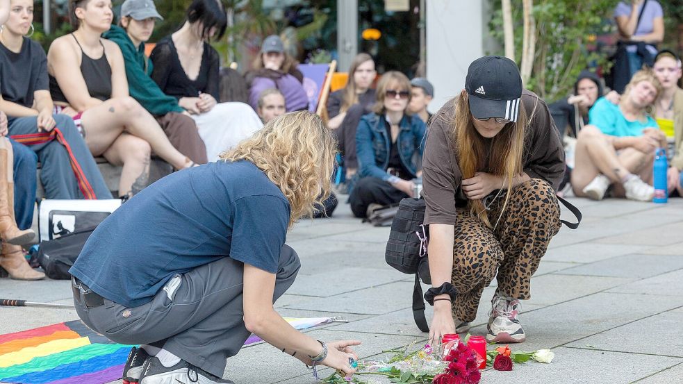 Blumen und brennende Kerzen werden bei der Mahnwache zum Anschlag auf den CSD in Berlin von Queer Pride Dresden und weiteren Gruppen auf den Boden vor einer Regenbogenfahne gelegt. Foto: DPA