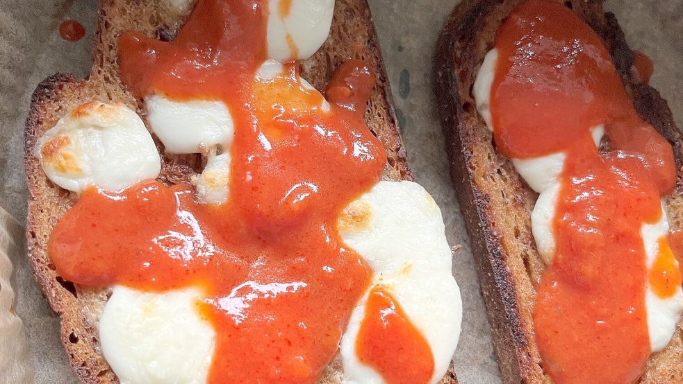 Auf die mit Mozzarella überbackenen Brotscheiben kommt aromatische Tomatensauce. Foto: Carmen Leonhard