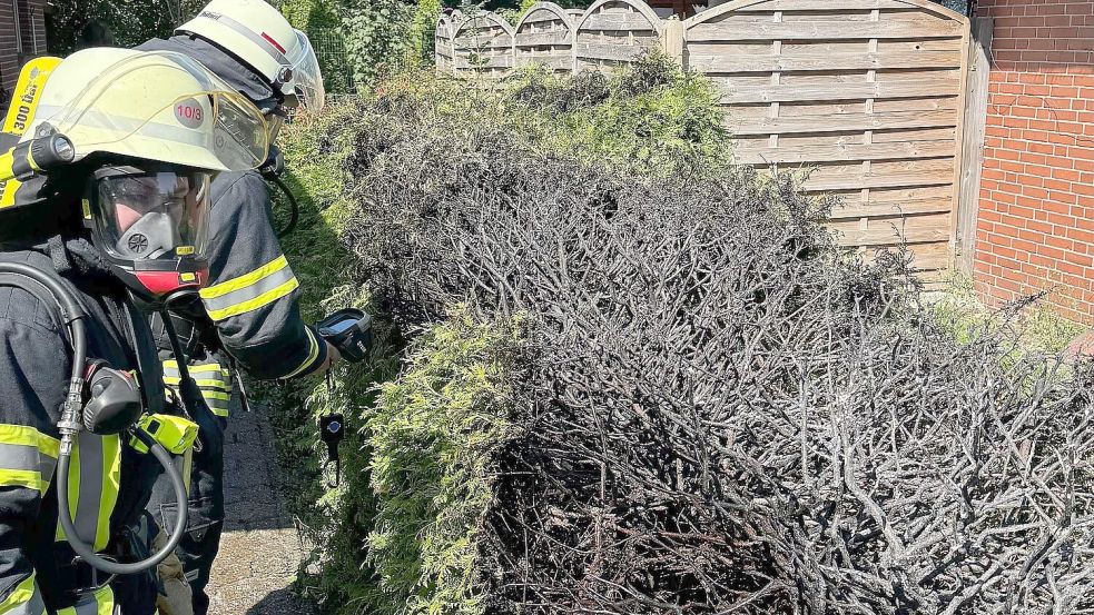Atemschutzgeräteträger der Feuerwehr Haxtum kontrollierten die bereits durch Anwohner erfolgreich gelöschte Hecke in der Straße Schwarzes Fehn. Foto: Keno Pollmann/Feuerwehr Haxtum
