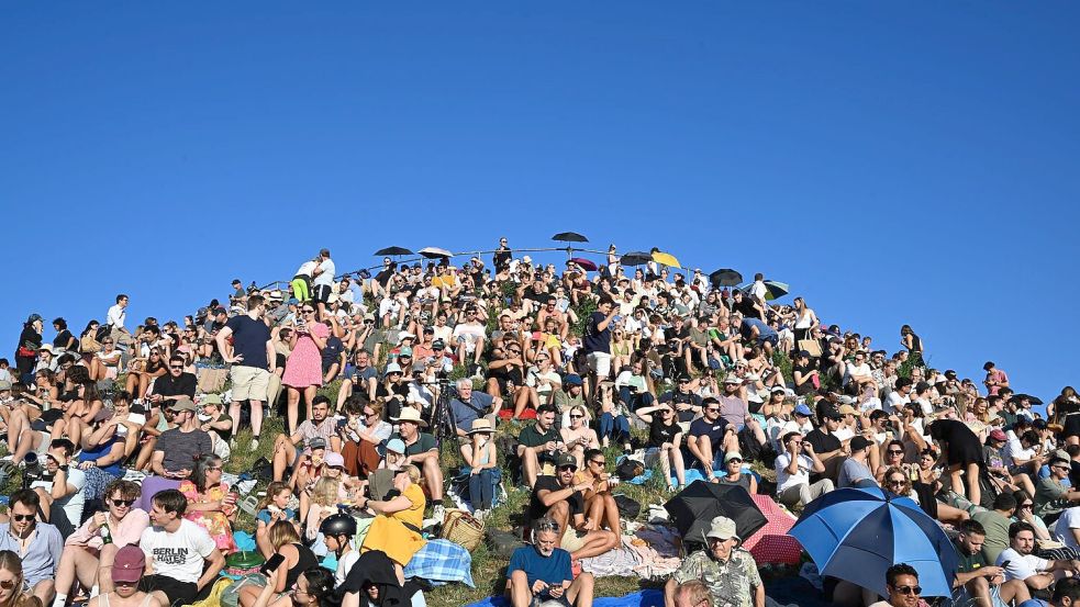 Menschen betrachten die partielle Sonnenfinsternis am Olympiaberg im Münchner Olympiapark. Foto: Felix Hörhager