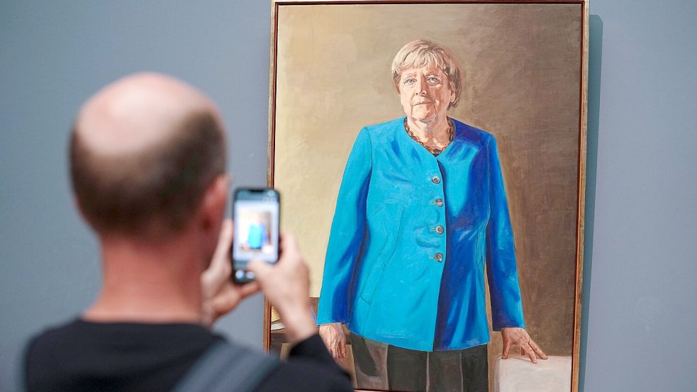 Mona Lisa auf Zeit: Ein Besucher macht mit dem Smartphone ein Foto vom Porträt der früheren Kanzlerin Merkel, das von Künstler Jérémie Queyras für die Ahnengalerie im Bundeskanzleramt gemalt wurde. Foto: dpa/Kay Nietfeld