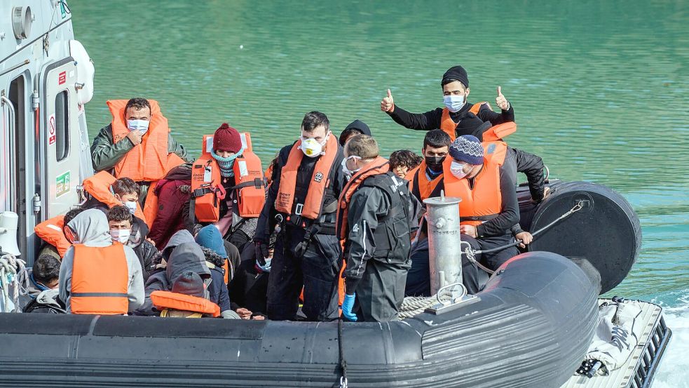 Sie haben es über den Ärmelkanal geschafft: Migranten, die von der britischen Grenzpolizei aufgegriffen worden sind, gehen in Dover an Land. Foto: IMAGO/Sean Aidan