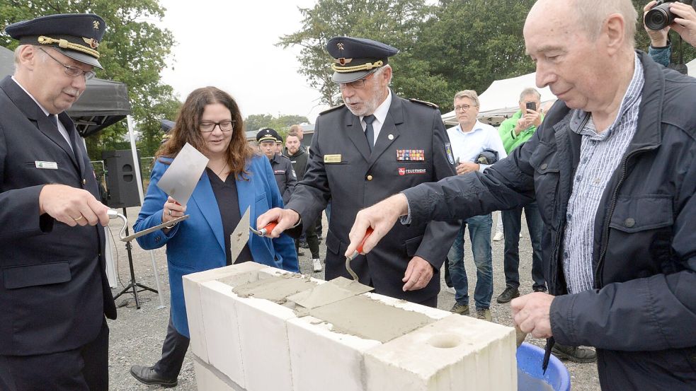 Alle packen bei der Grundsteinlegung für die FTZ in Brinkum mit an: Kreisbrandmeister Ernst Berends (von links), die Kreistagsvorsitzende und Bundestagsabgeordnete Anja Troff-Schaffarzyk (SPD), der ehemalige Kreisbrandmeister Folkmar Hellmers und Johann Duis, Vorsitzender des Feuerschutzausschusses (CDU). Foto: Karin Lüppen