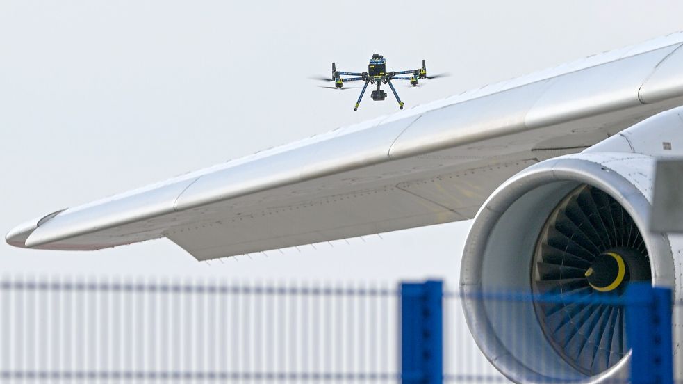 Eine Drohne der Polizei ist über einer Flugzeugtragfläche zu sehen. Foto: dpa/Hendrik Schmidt