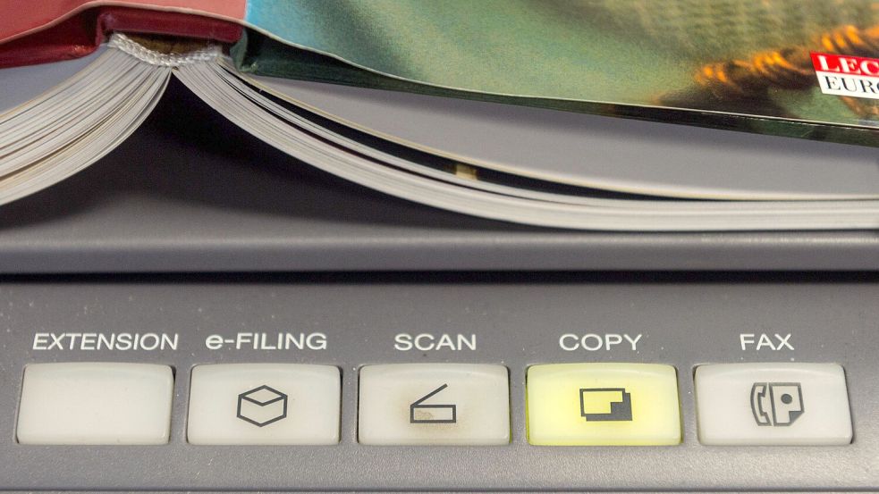 Ein Buch liegt auf einem Multifunktionsdrucker: KI-Unternehmen verbrauchen gerade antiquarische Bücher. Foto: Armin Weigel/dpa