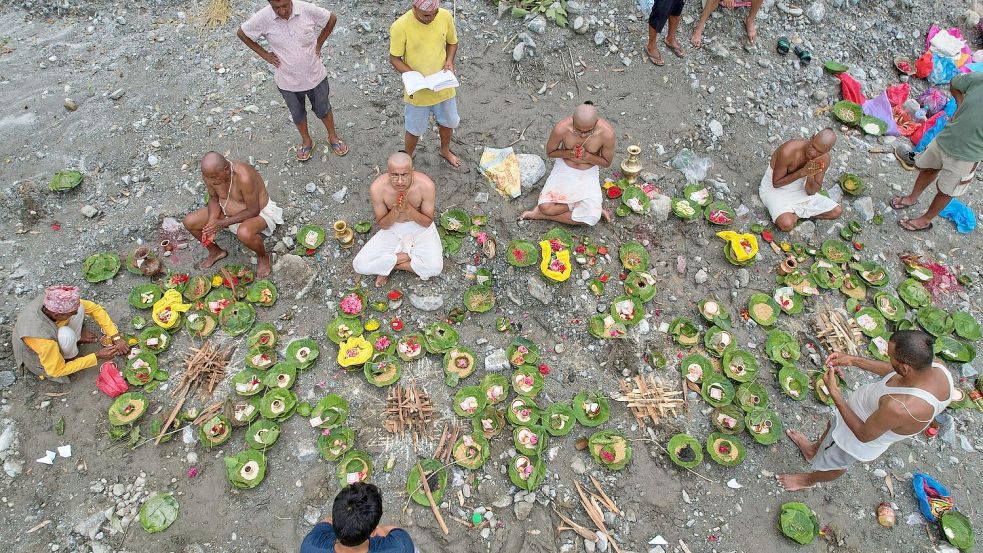 Menschen, deren Angehörige nach den Sturzfluten weiterhin vermisst werden, vollziehen am Ufer des angeschwollenen Trishuli-Flusses im nepalesischen Distrikt Nuwakot Rituale im Anschluss an symbolische Bestattungszeremonien. Foto: Rajesh Kumar Singh