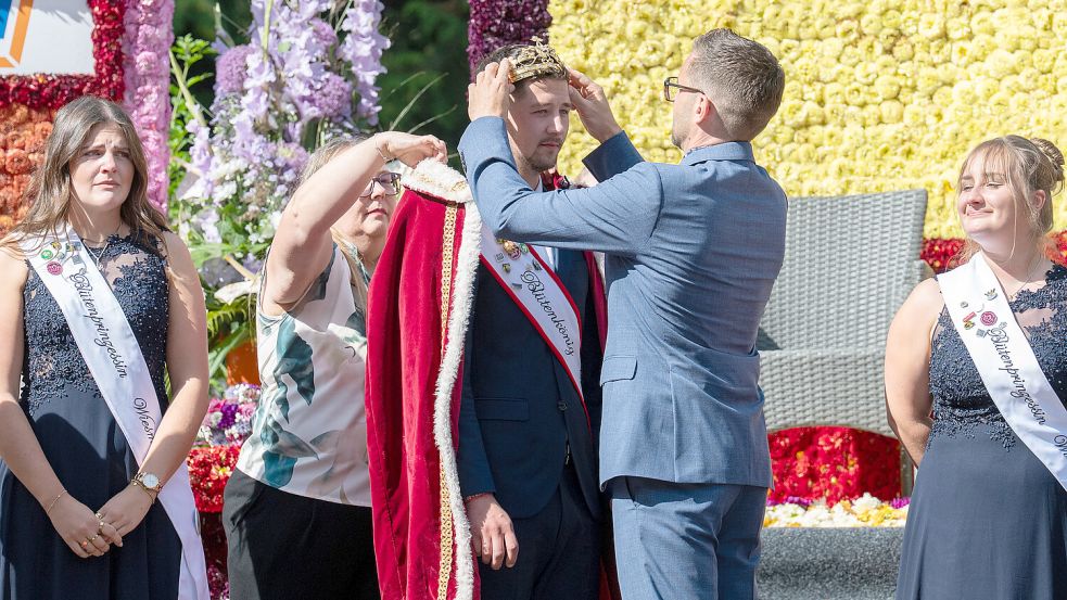 Abschied auf der Freilichtbühne: Bürgermeister Sven Lübbers und Anke Saathoff nehmen dem scheidenden Blütenkönig Henrik Broers Krone und Mantel ab. Links wirkt Prinzessin Lea Aggen sichtlich traurig, rechts versucht Kimberly Kolod, Haltung zu bewahren. Foto: Klaus Ortgies