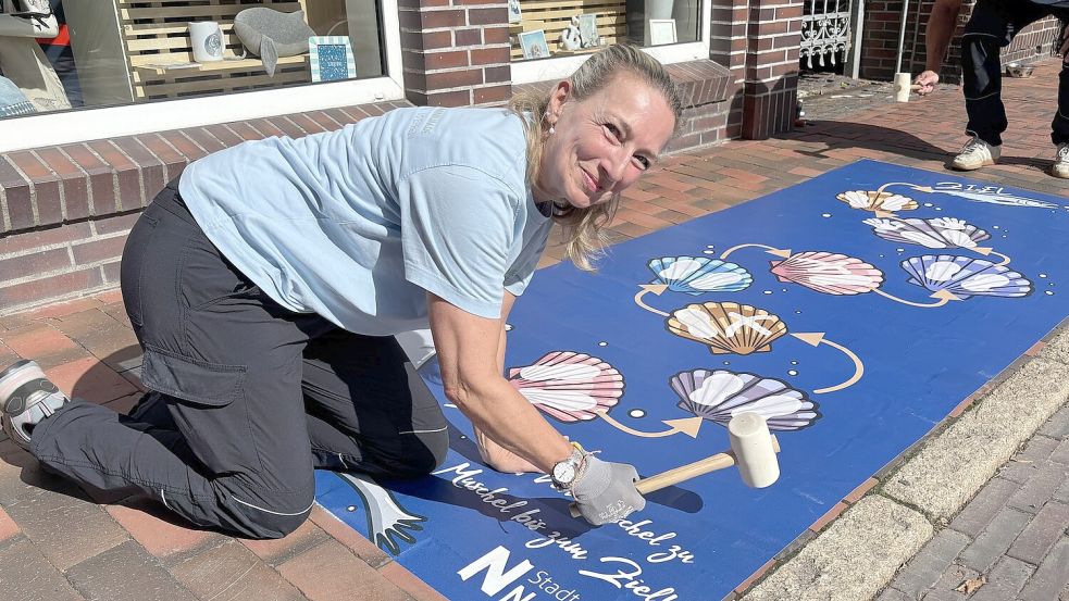 Esther Kramer klopft die Aluminiumfolie auf dem Gehweg fest. Foto: Rebecca Kresse