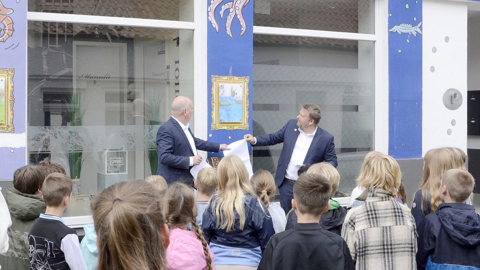 Bürgermeister Claus-Peter Horst (links) und Verkaufsleiter Andy Kampen enthüllten die Malerein der Grundschüler. Foto: privat